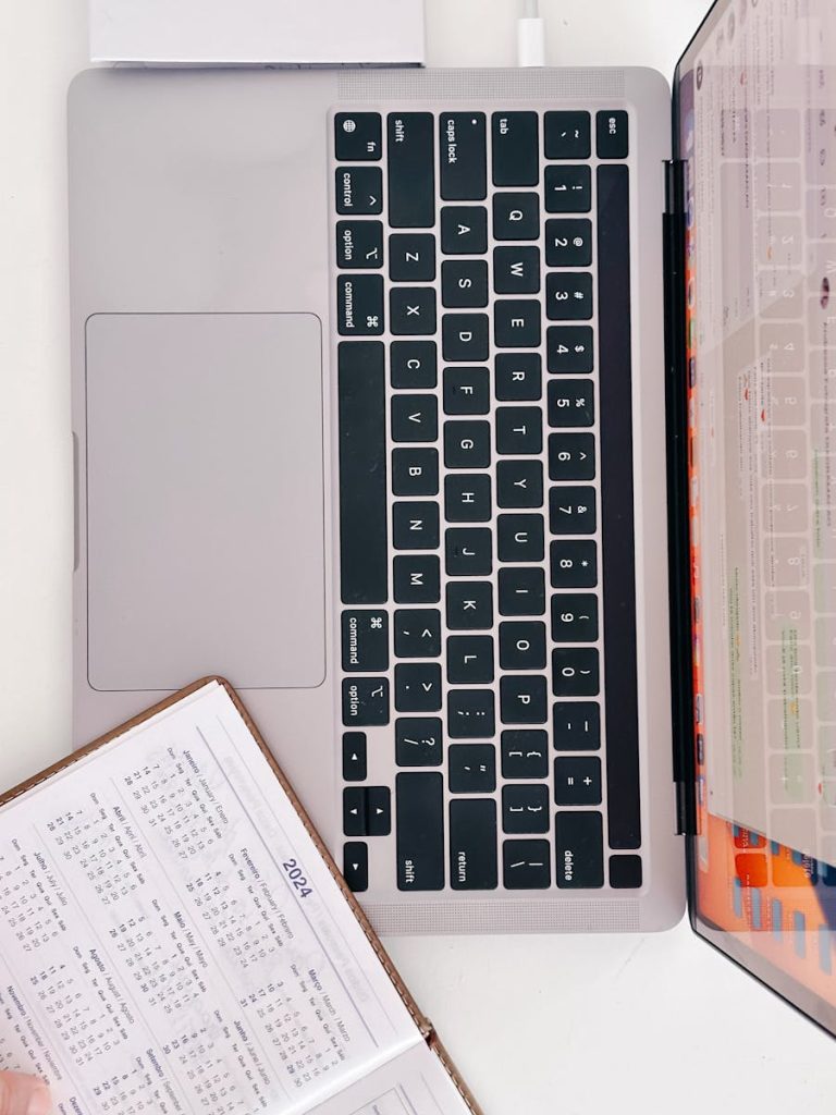 A person is using a laptop and a notebook