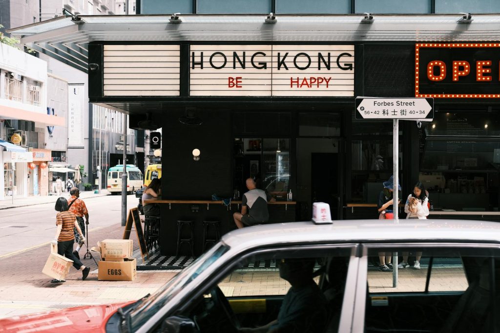 A car drives past a restaurant with a sign that says hong kong