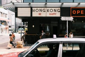 A car drives past a restaurant with a sign that says hong kong